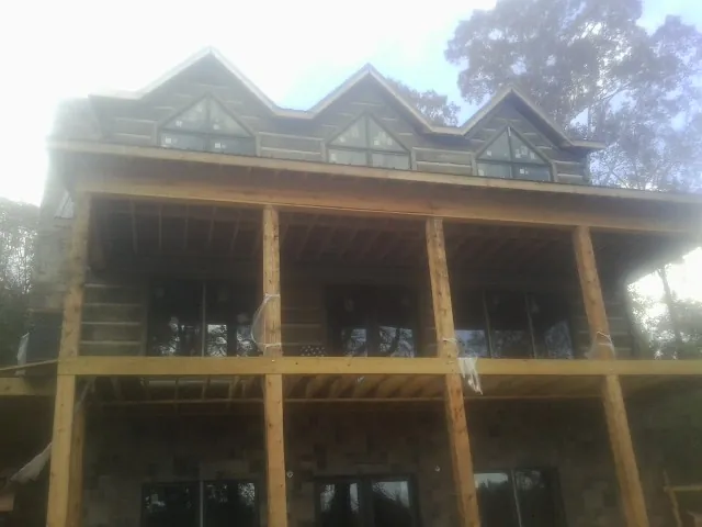Dormers and porch framing on a large log home under construction — Roof Coating work by our crew in Ute