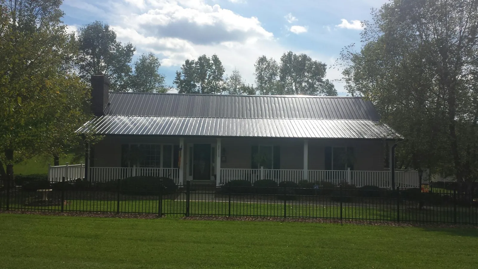 Gray metal roof on a brick ranch with a full width front porch — Gutter Guard Installation work by our crew in Ute