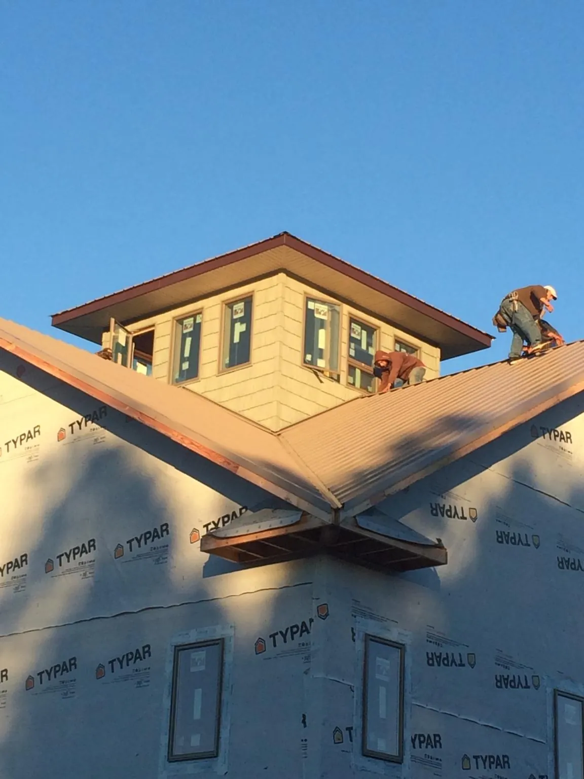Roofers working around a rooftop cupola on a new metal roof at sunset — Roof Waterproofing in Ute by Roofing Brothers